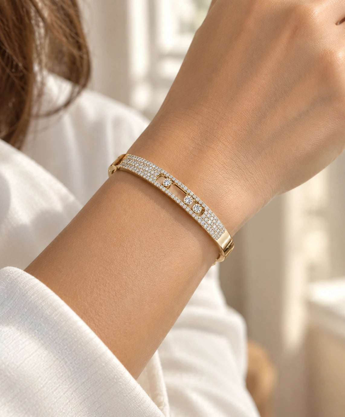 Yellow gold pavé diamond bangle with three floating diamonds worn on a wrist