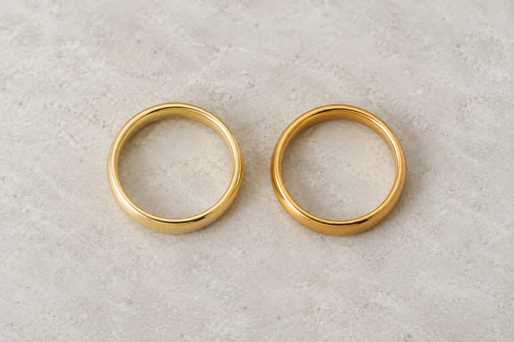 14K vs 18K gold wedding bands side by side: paler 14K gold on the left, richer 18K gold on the right