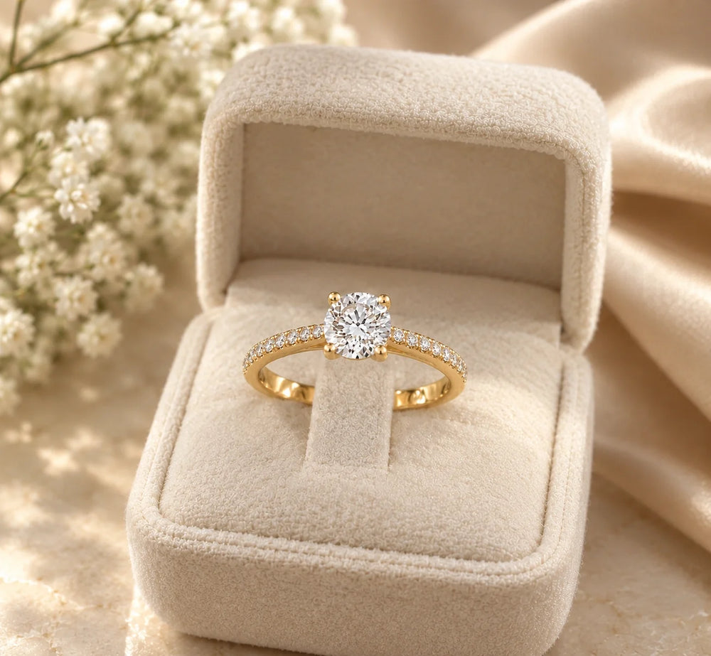 Round solitaire engagement ring in 14K yellow gold with a pavé diamond band, in a velvet ring box