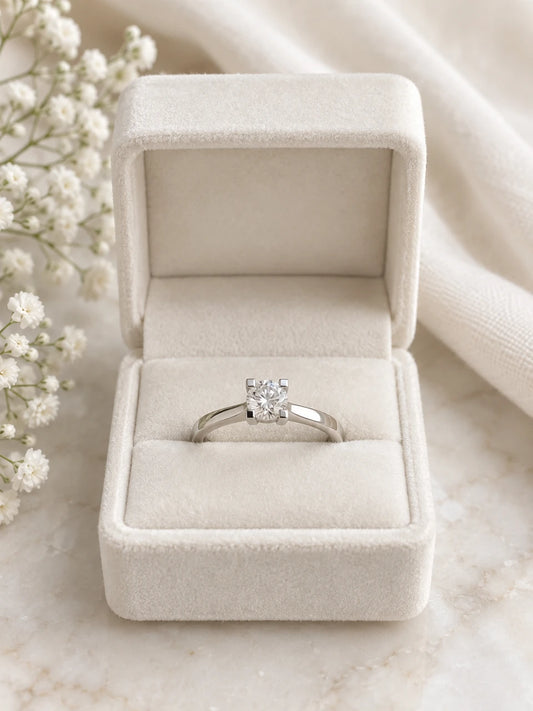 Classic solitaire engagement ring in white gold with a round diamond, in a cream velvet box