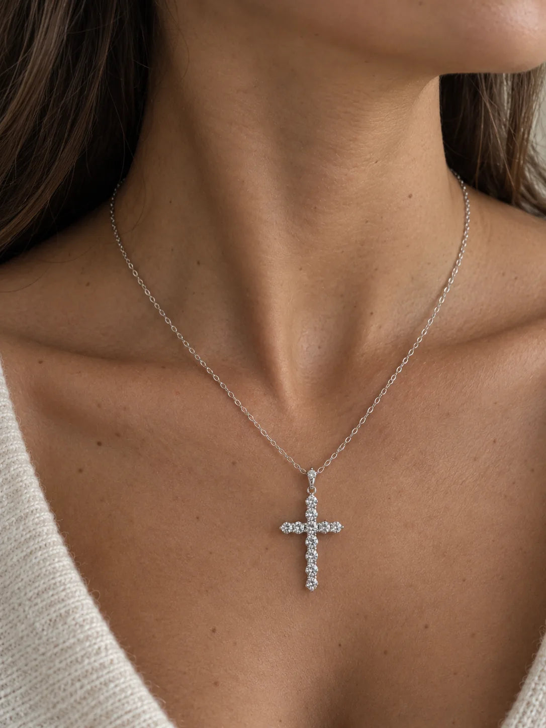 Diamond cross necklace in 18K white gold worn on a woman's neck