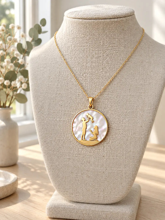 Family pendant necklace in 14K gold: father lifting a child with mother kneeling, on mother-of-pearl, on a linen bust