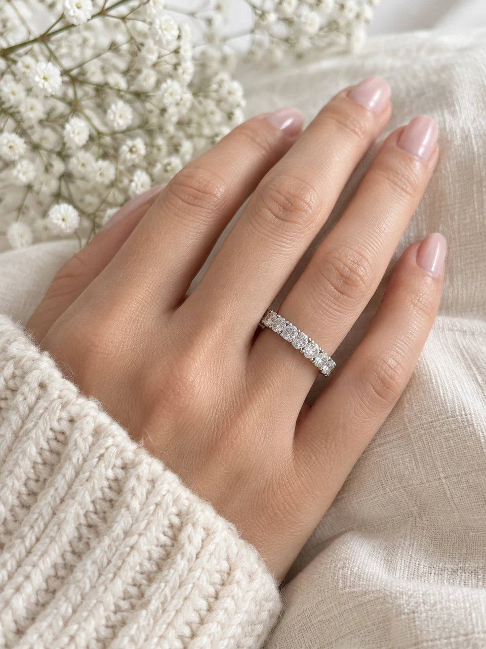 White gold half eternity diamond band worn on a hand