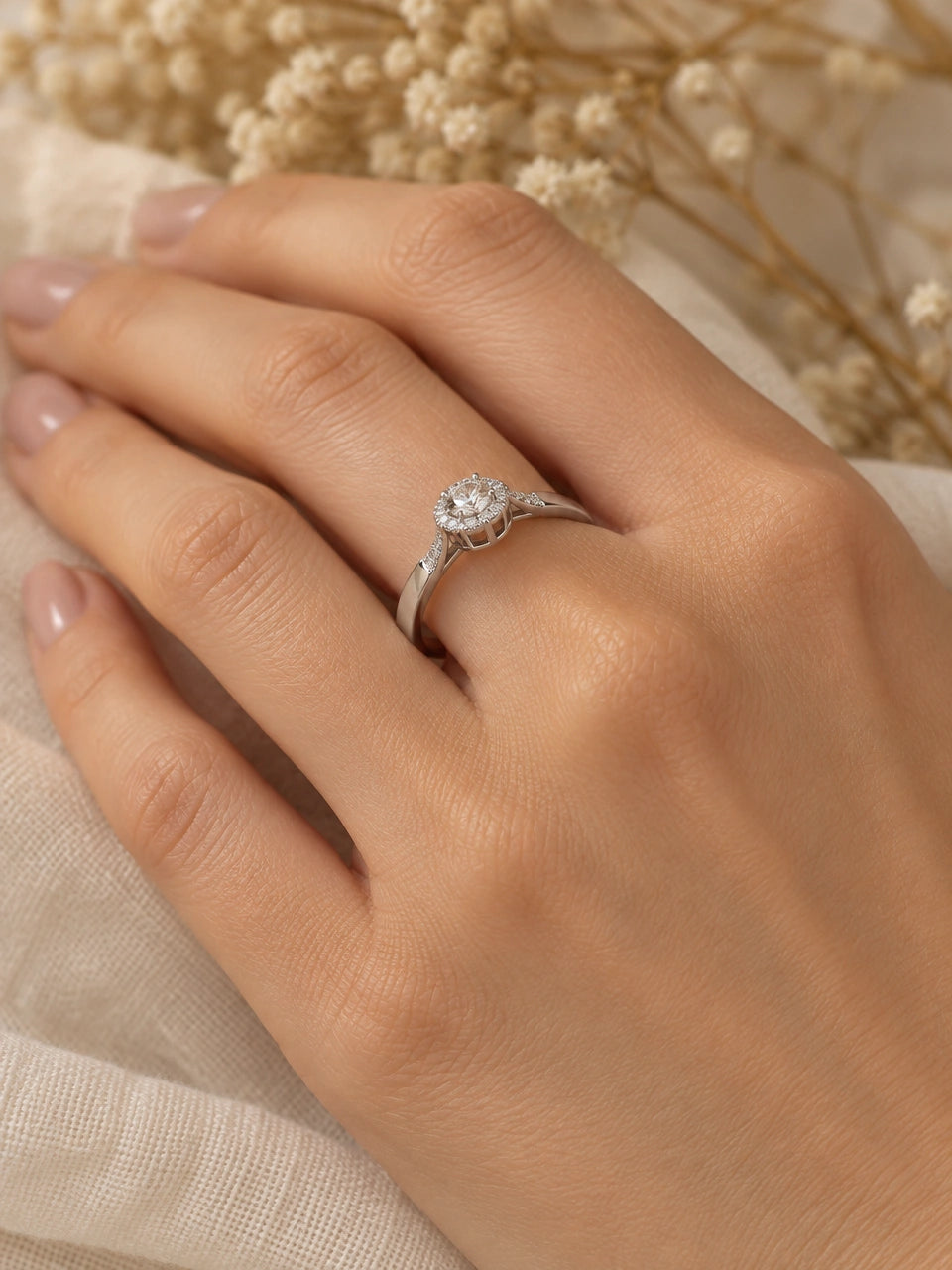 White gold hidden halo engagement ring worn on a woman's ring finger