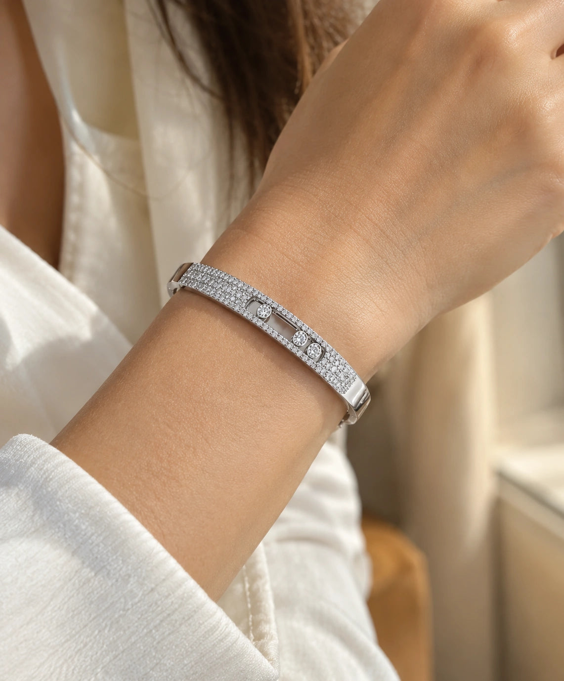 White gold pavé diamond bangle with three floating diamonds worn on a wrist