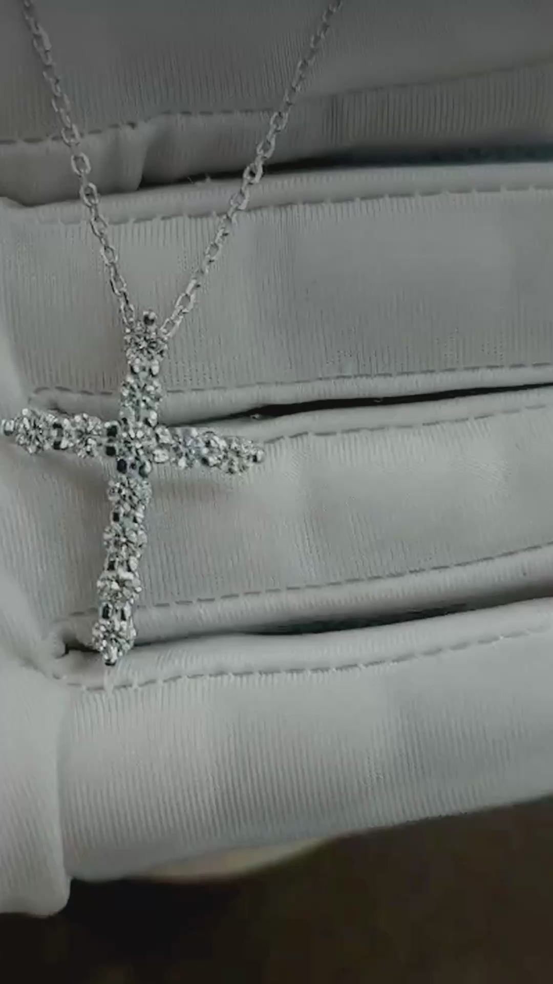 Close-up video of the 18K white gold diamond cross necklace on a glove and on a display bust