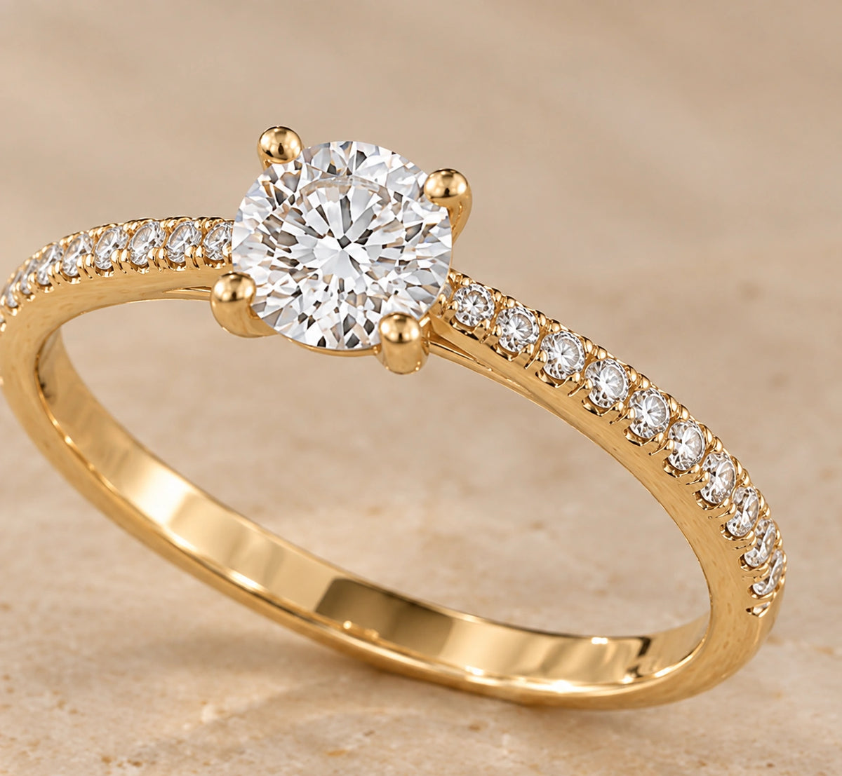 Close-up of a round brilliant diamond solitaire in 14K yellow gold with pavé diamonds on the shoulders