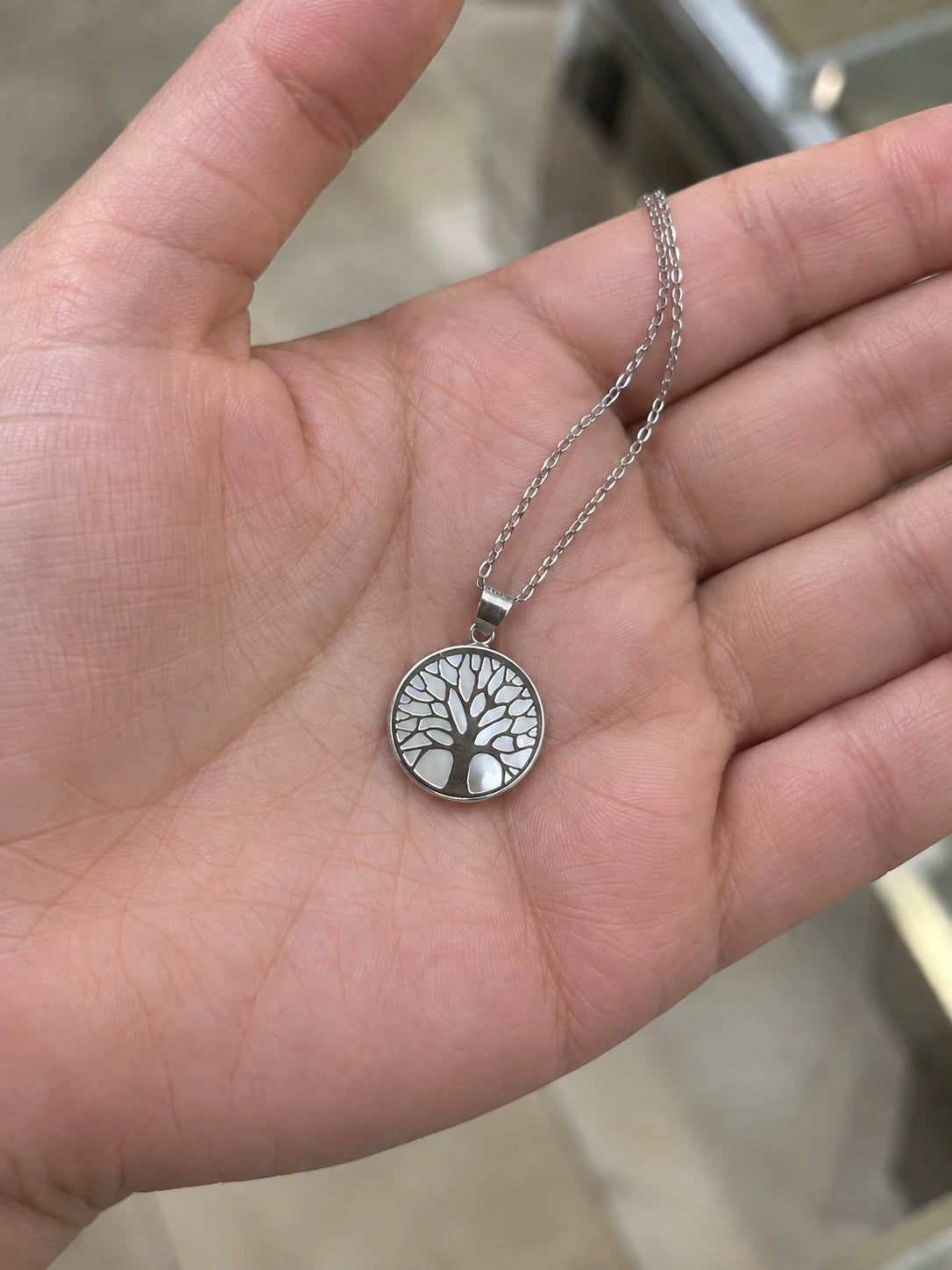 14K white gold Tree of Life pendant necklace held in a hand to show its size