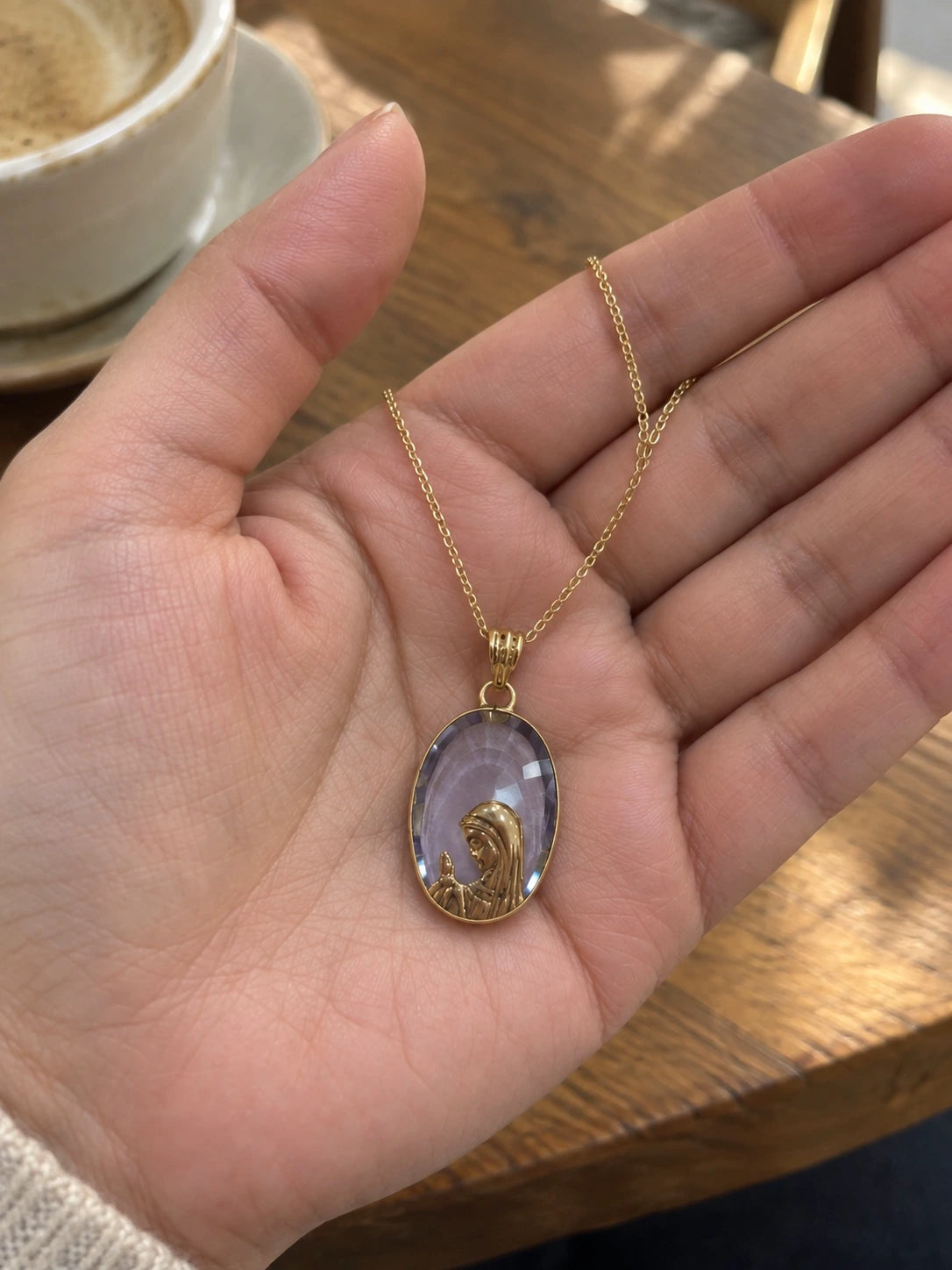 Lavender stone Virgin Mary pendant necklace in 14K gold held in a hand to show its size